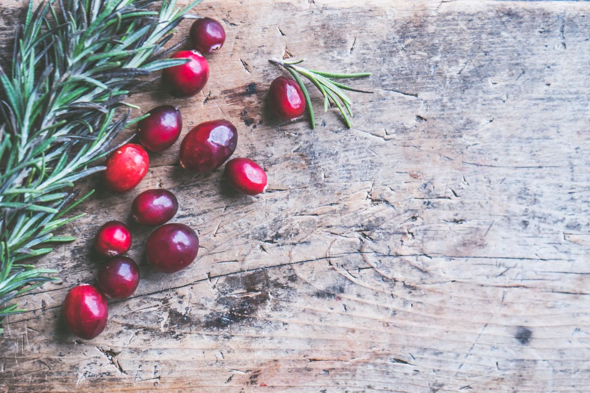 Fresh cranberries and rosemary on a rustic wooden surface