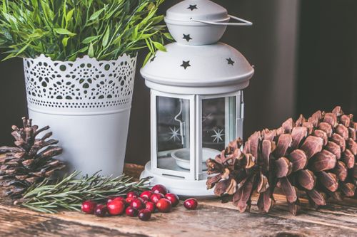 Free Close-up of a rustic indoor scene with candle lantern, pine cones, and greenery on wooden surface. Stock Photo
