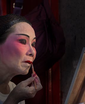Asian woman applying traditional stage makeup with precision, makes for a captivating cultural visual.