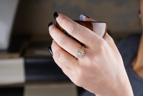 A Close-Up Shot of a Person Wearing a Diamond Ring Holding a Cup