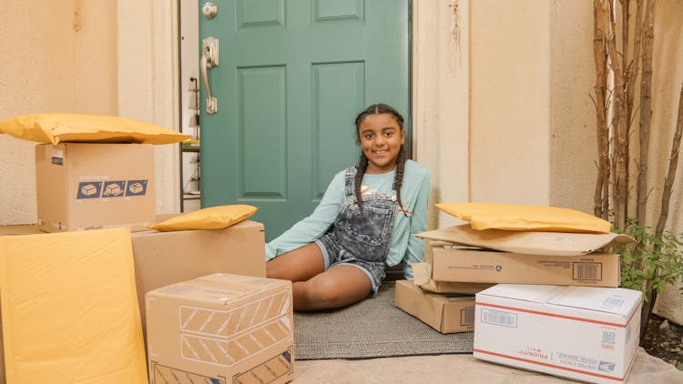 
A Girl Sitting On A Porch With Parcels