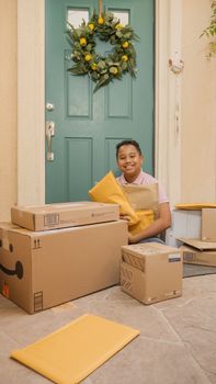 Smiling child sitting with multiple packages on a porch, green door background.