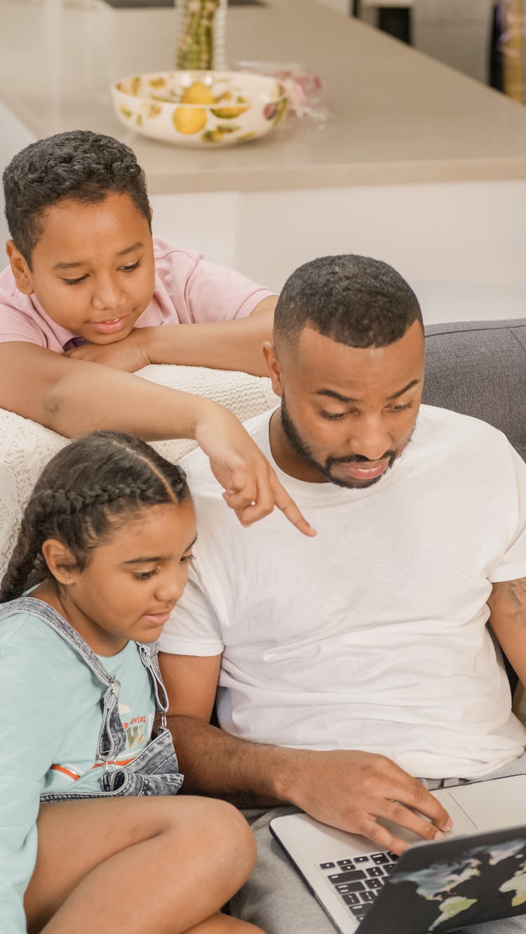 A Father And Children Looking The Laptop Together 