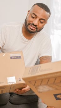 Bearded man holding and sorting packages at home, ideal for delivery or logistics themes.