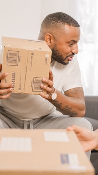 A man in casual attire happily receives a package indoors. Perfect for delivery and logistics themes.