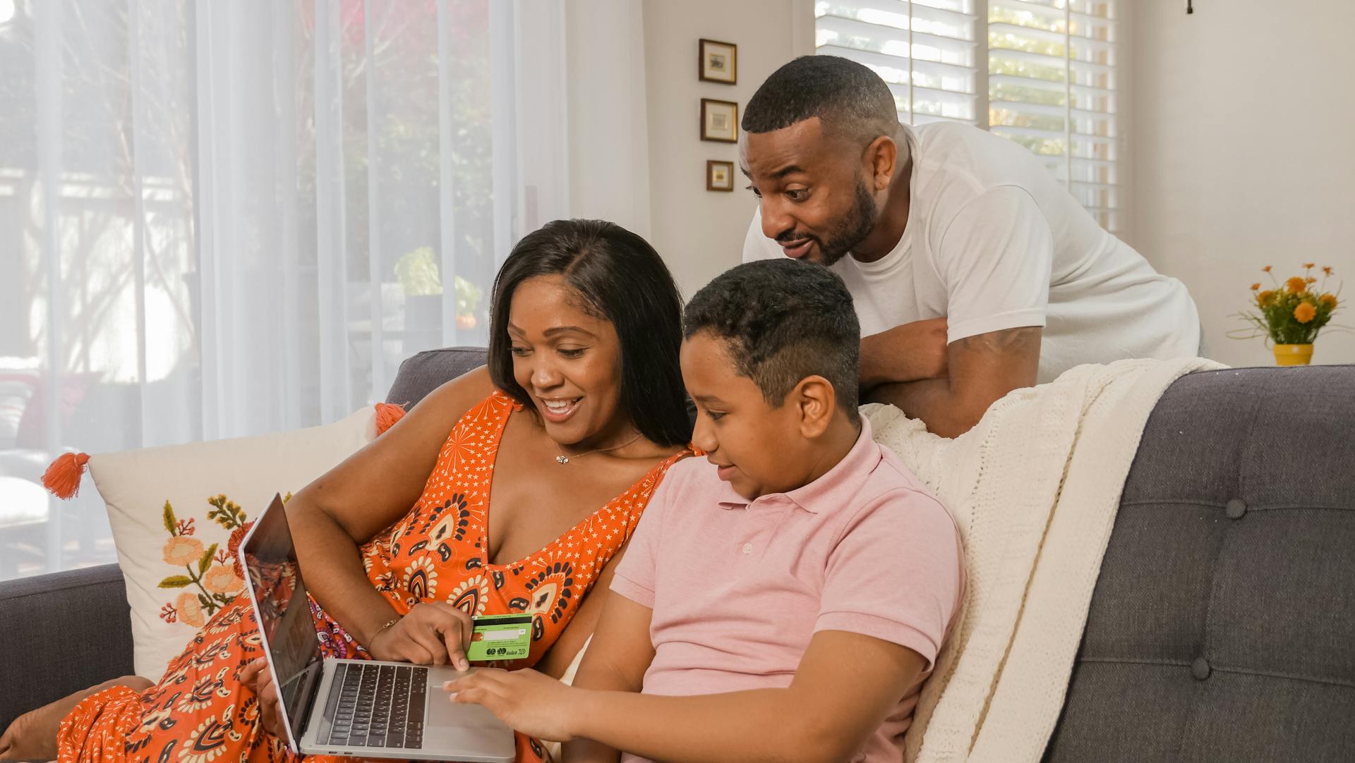 A joyful family making an online purchase together on a laptop at their cozy home.