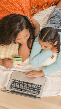 African American mother and daughter shopping online using a laptop in a cozy home setting.