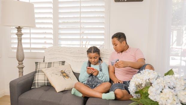 Two children using a smartphone for online shopping in a cozy living room setting.