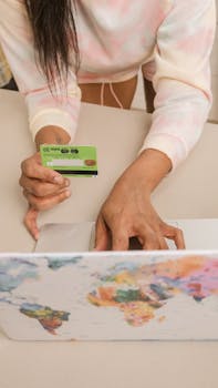 An adult using a credit card for online shopping on a laptop.