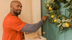 Man in Orange Shirt Knocking on Door Making a Delivery