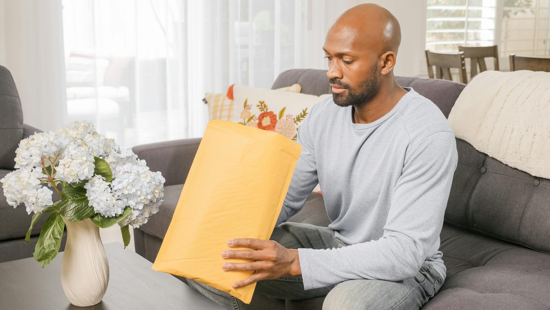 A Man Opening an Package while Sitting on a Couch