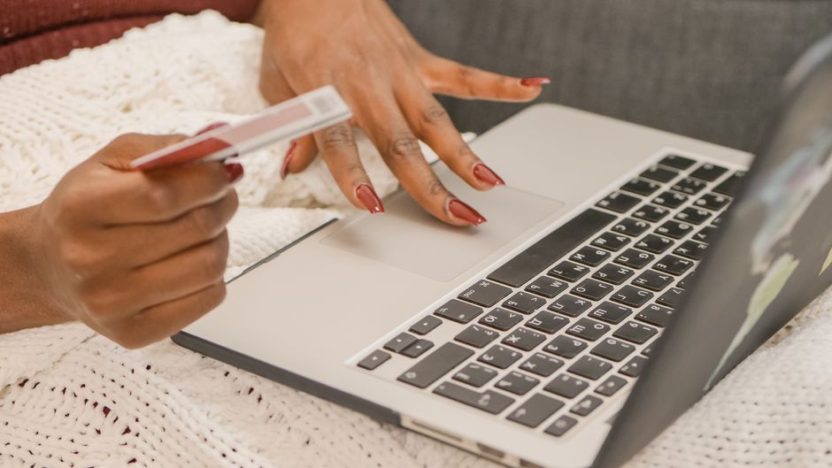 A person uses a credit card for online shopping on a laptop, highlighting digital convenience. A person uses a credit card for online shopping on a laptop, highlighting digital convenience.
