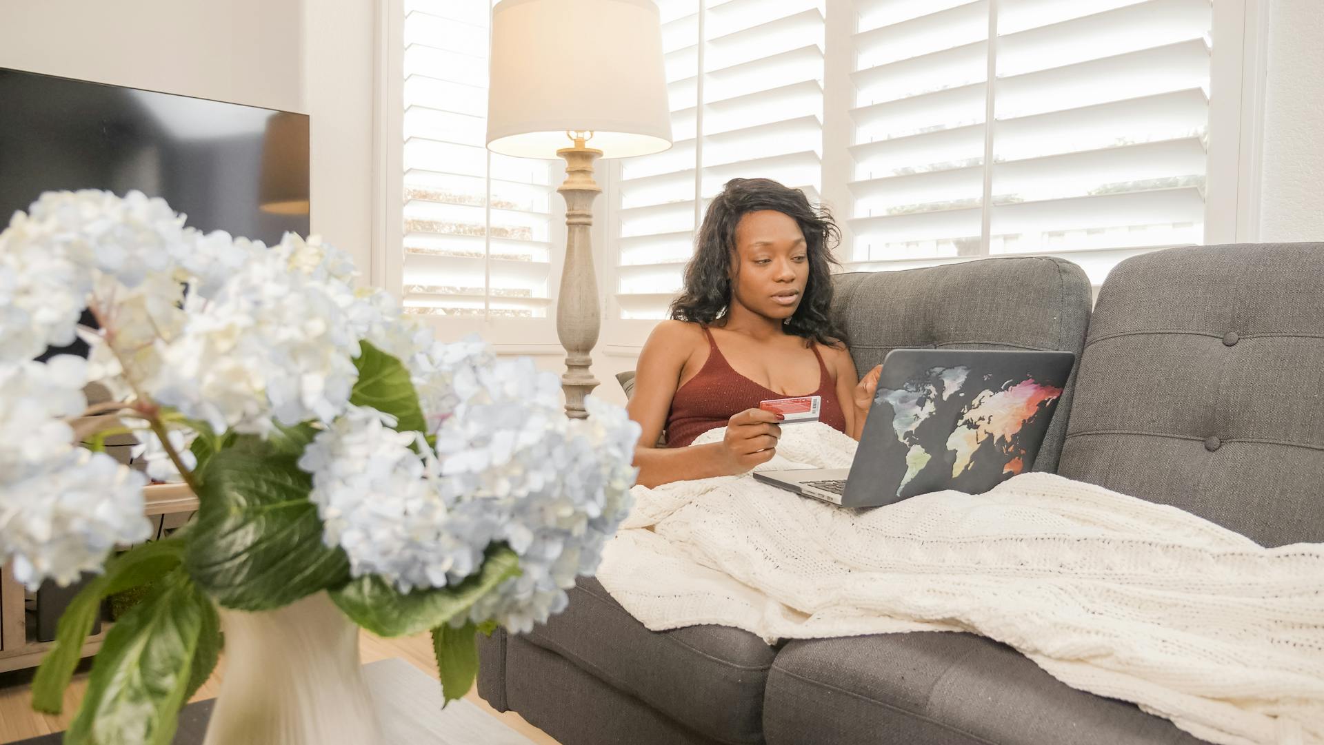 African American woman using a laptop and credit card for online shopping at home.