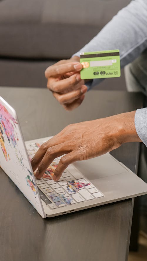 Free Photo of a Person's Hands Holding a Credit Card Near a Laptop Stock Photo