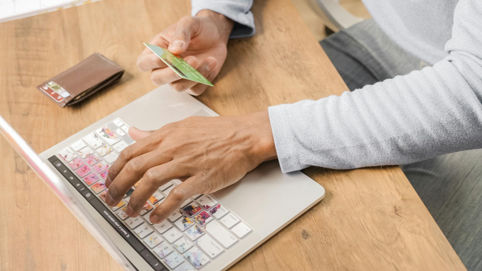 A person using a laptop while holding a credit card for online shopping. Perfect for illustrating e-commerce concepts.