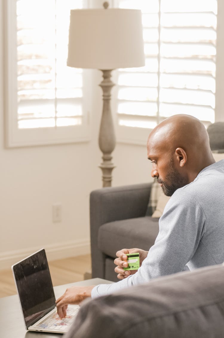 A Man Holding A Credit Card Buying Online