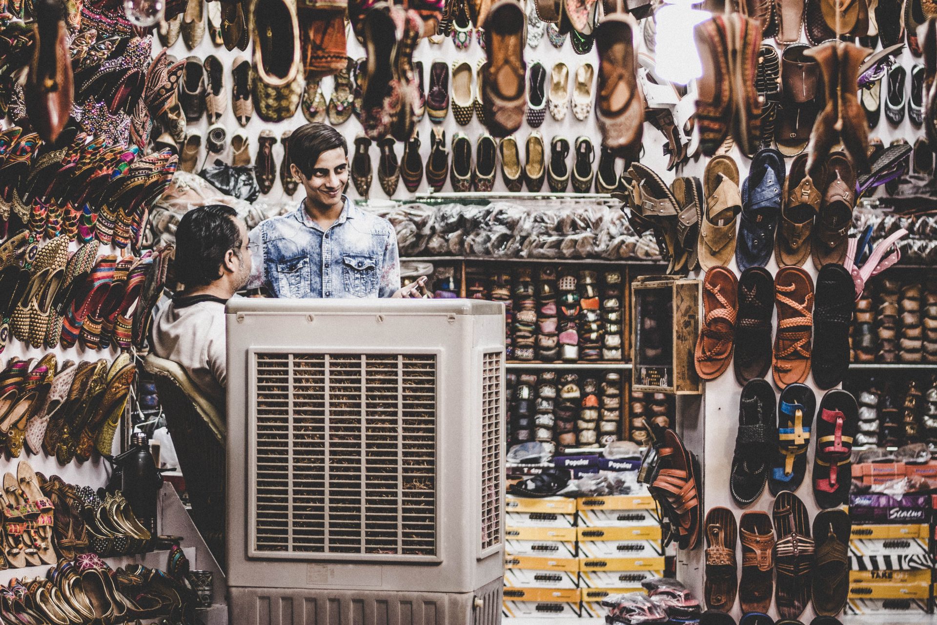 Explore the lively shoe market in Pushkar, India, showcasing diverse footwear and smiling vendors.