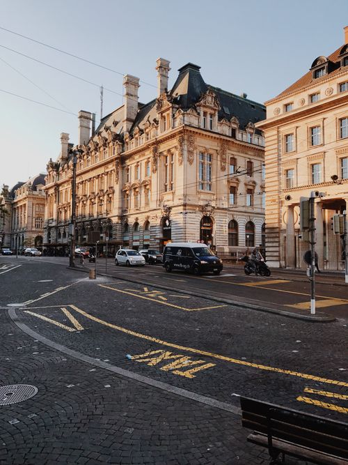 Free Elegant European city street with historic architecture and vehicles in morning light. Stock Photo