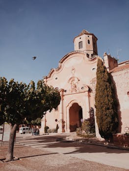在晴朗的天空下，一座风景如画的历史教堂被郁郁葱葱的树木环绕，这张照片拍摄于白天