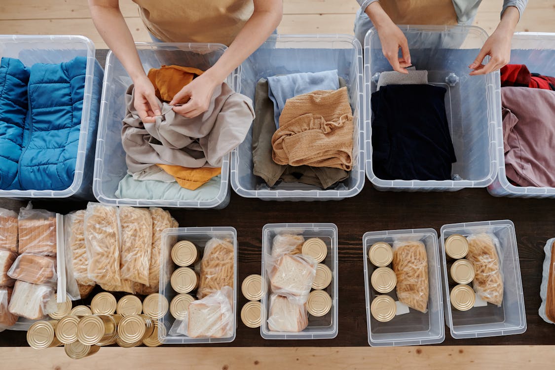 Free Clothing in Plastic Containers and Food in Cans on Table Stock Photo