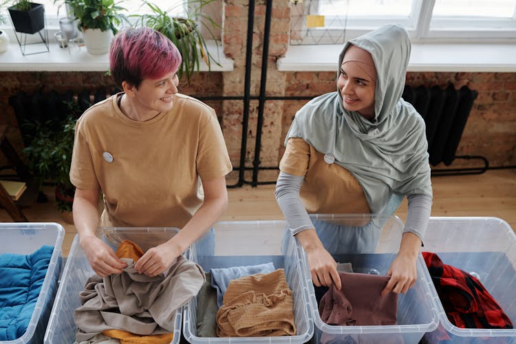 Women Sorting Clothes And Smiling To Each Other