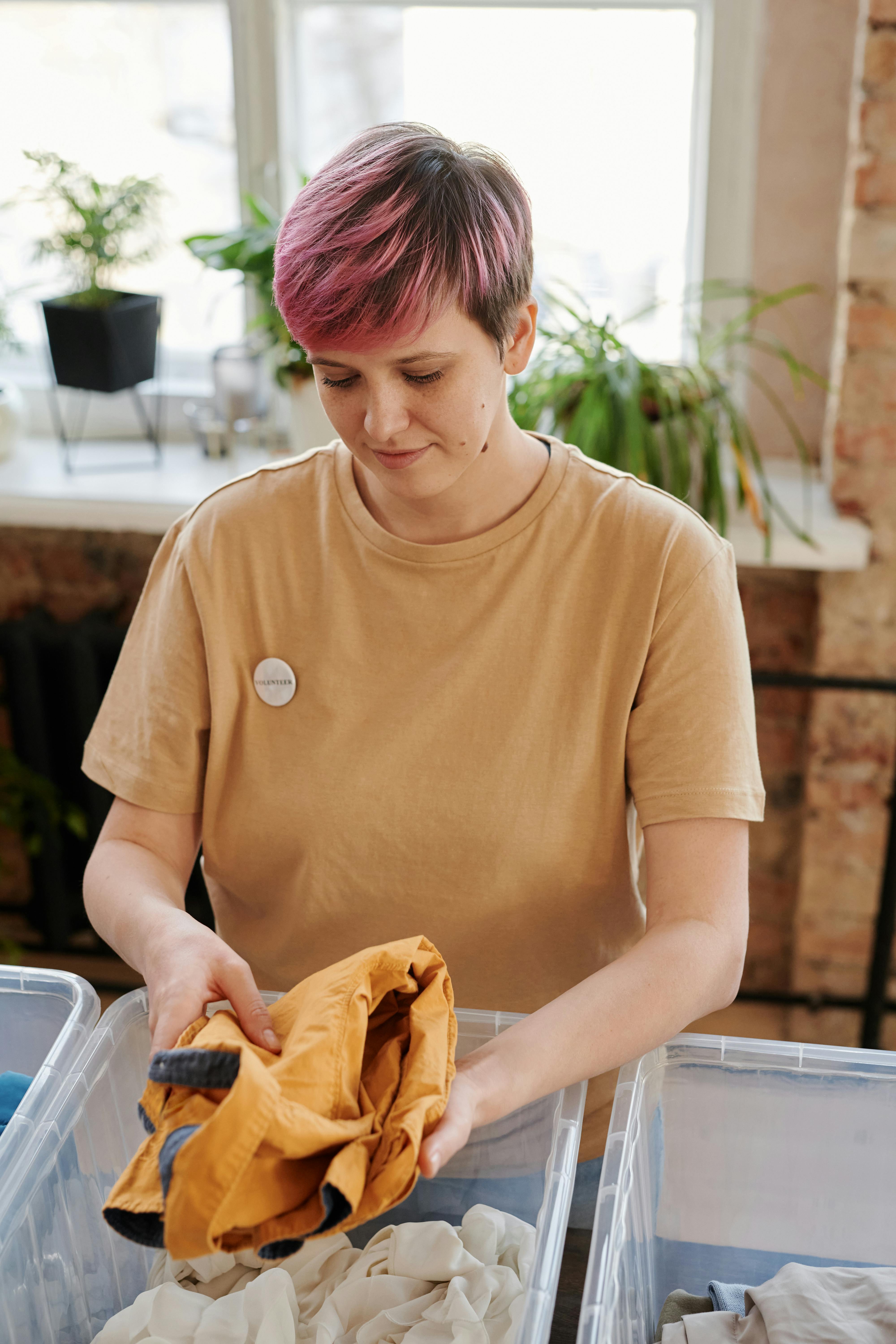 woman with pink hair sorting clothes