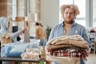 A Bearded Man Holding a Pile of Folded Scarfs