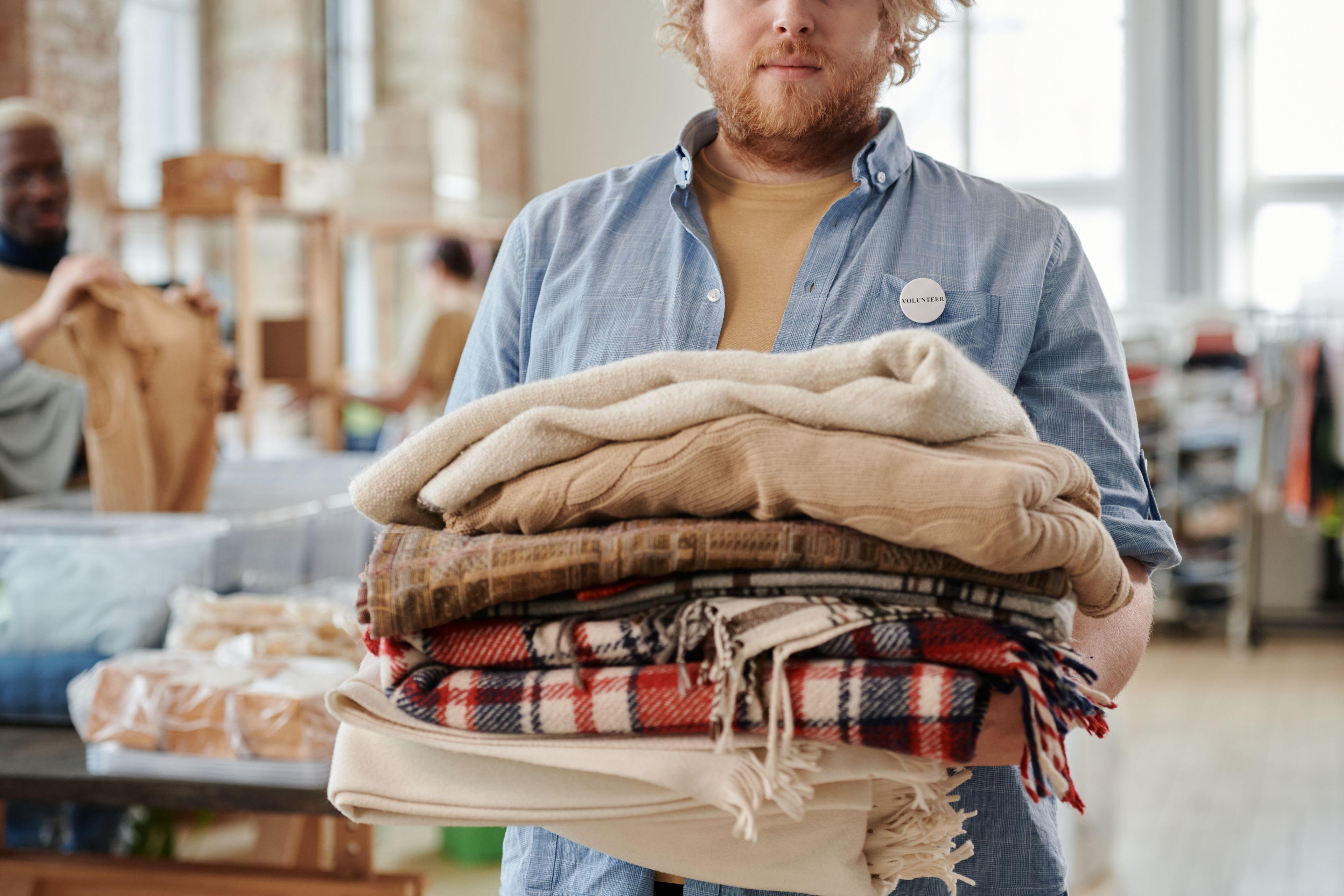 A volunteer holding a pile of folded blankets