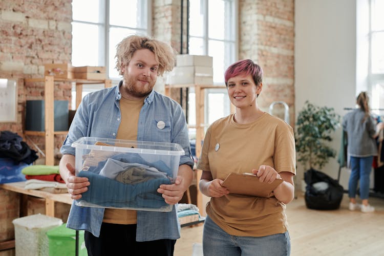 Man And Woman Volunteers With Box Of Clothes