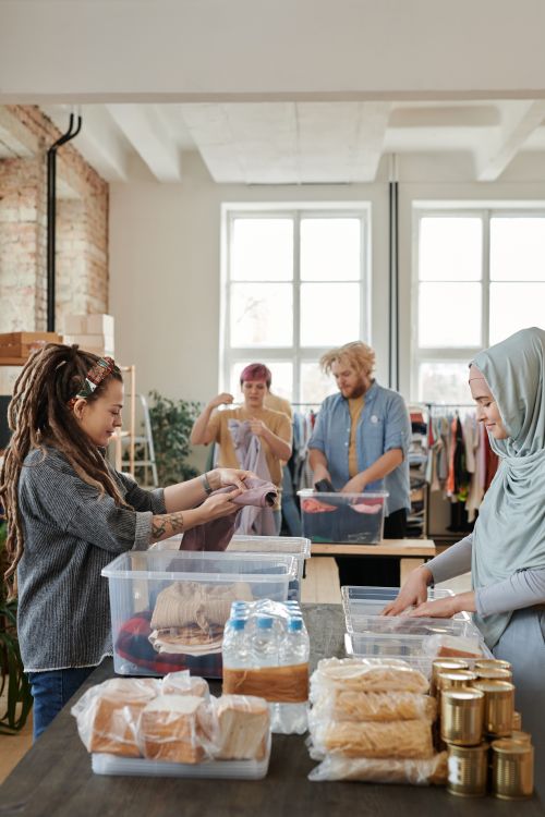 Free A diverse group of volunteers sorting clothes and food items at an indoor donation center. Stock Photo