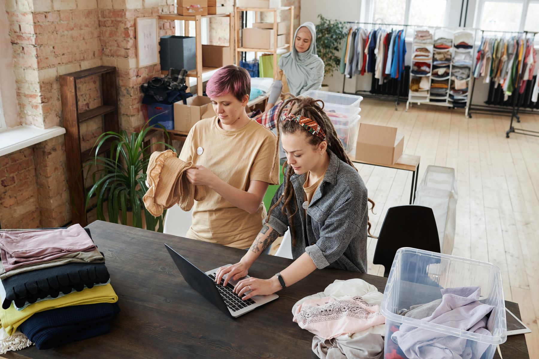Nonprofit volunteers organizing donations while using a laptop