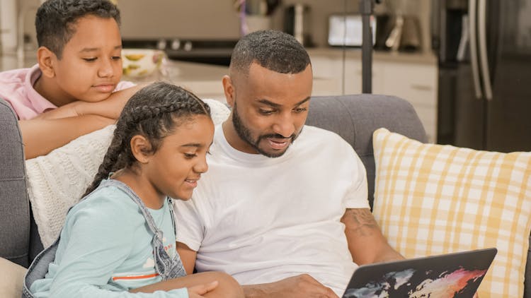 A Father And Children Using A Laptop