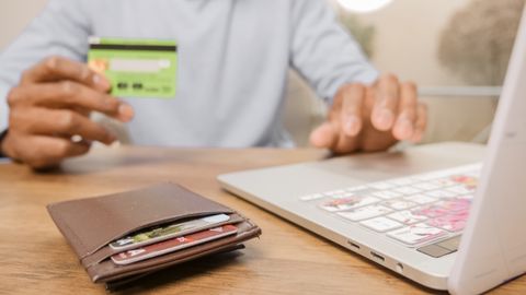 Close-up of hands with a bank card and laptop for online shopping. Perfect for illustrating e-commerce concepts.