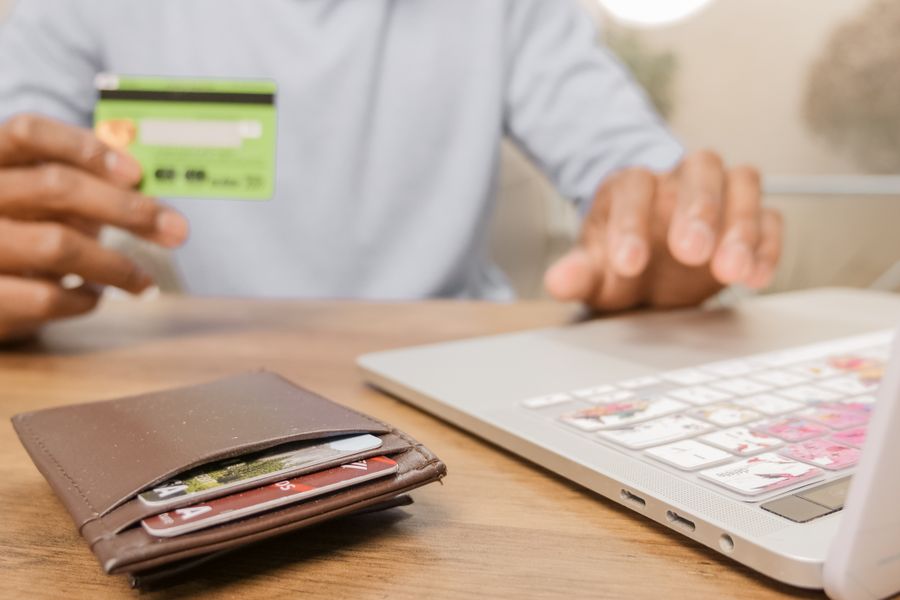 Close-up of hands with a bank card and laptop for online shopping. Perfect for illustrating e-commerce concepts.