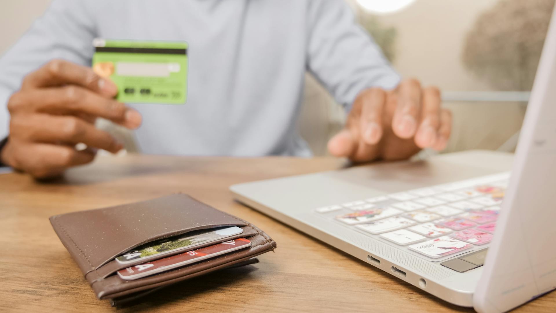 Close-up of hands with a bank card and laptop for online shopping. Perfect for illustrating e-commerce concepts.