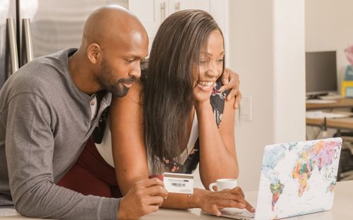 Free Smiling couple making an online purchase using a laptop and bank card indoors. Stock Photo