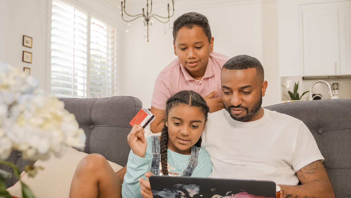 Black father teaching his children about safe online financial activity