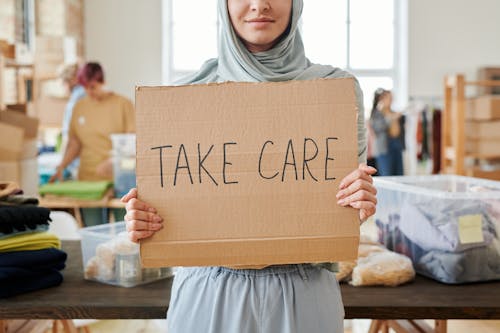 Free Person in Gray Hijab Holding Brown Cardboard with Text Stock Photo