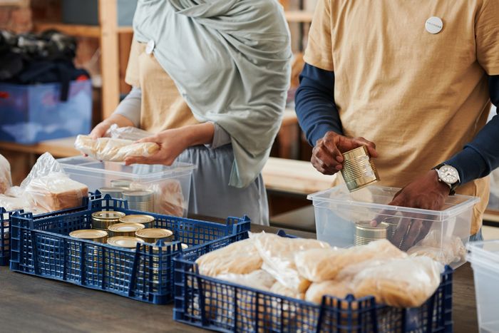 Two volunteers, one wearing hijab, sorting canned goods and bread into donation crates