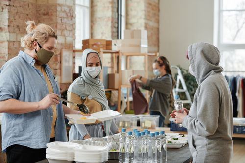 Free A diverse group of volunteers prepare and distribute food and drinks at an indoor community center. Stock Photo