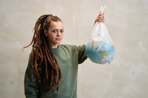 Free A woman with dreadlocks holding a globe in a plastic bag, symbolizing environmental awareness. Stock Photo