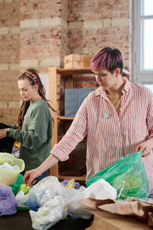 Women Sorting Recyclable Materials While Holding a Plastic Bag