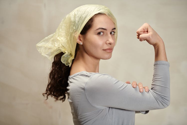 A Woman With Plastic On Head Flexing Her Bicep