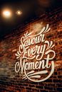 White signboard with Savour Every Moment inscription with creative design hanging on weathered brick wall in cafeteria with glowing lights