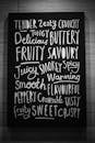 Black and white of creative signboard with various written words describing taste sensations placed at wall in modern light cafeteria
