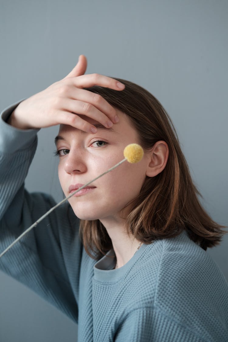 Young Woman With Decorative Pompom On Stick In Studio