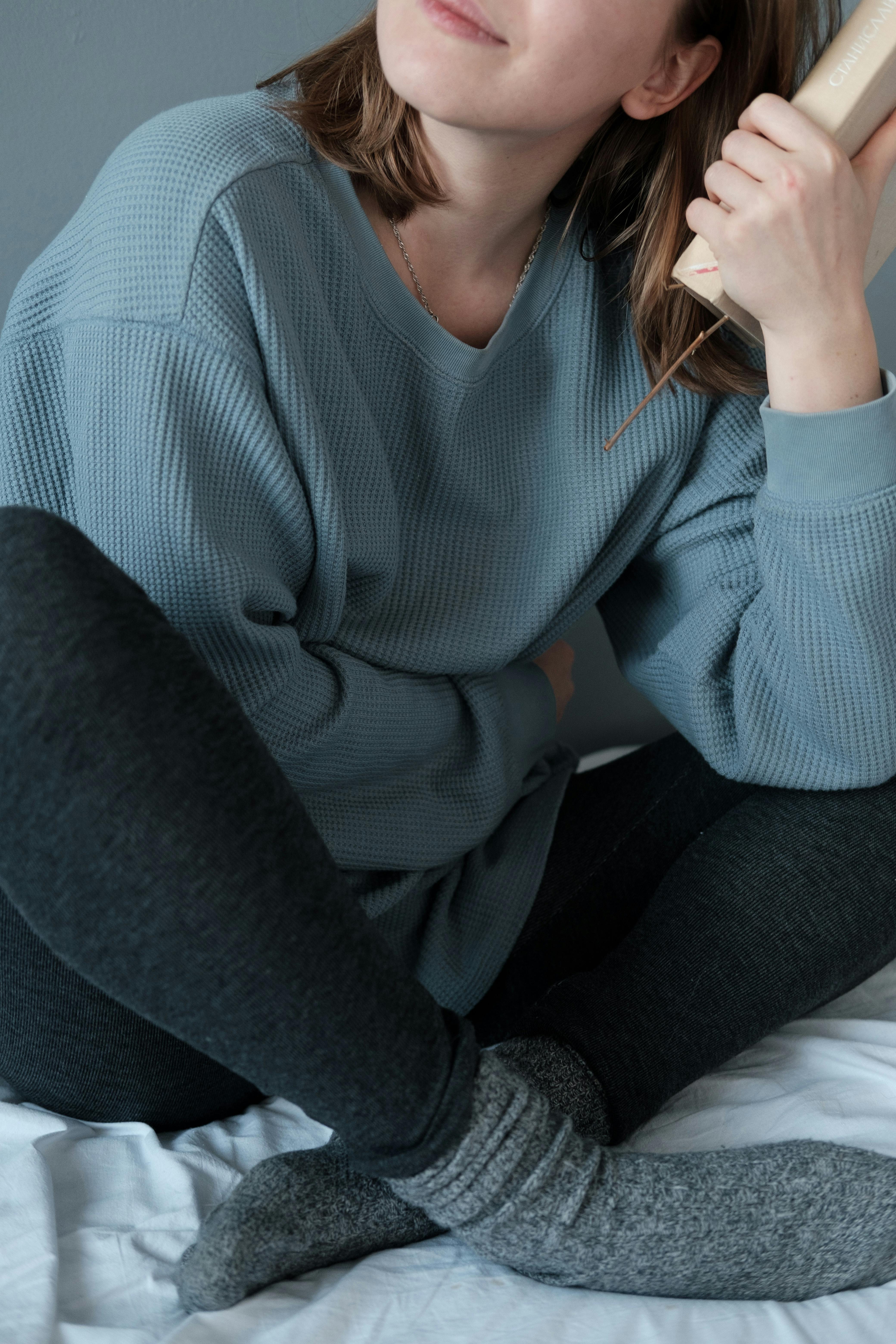 teenage girl sitting on bed and holding book