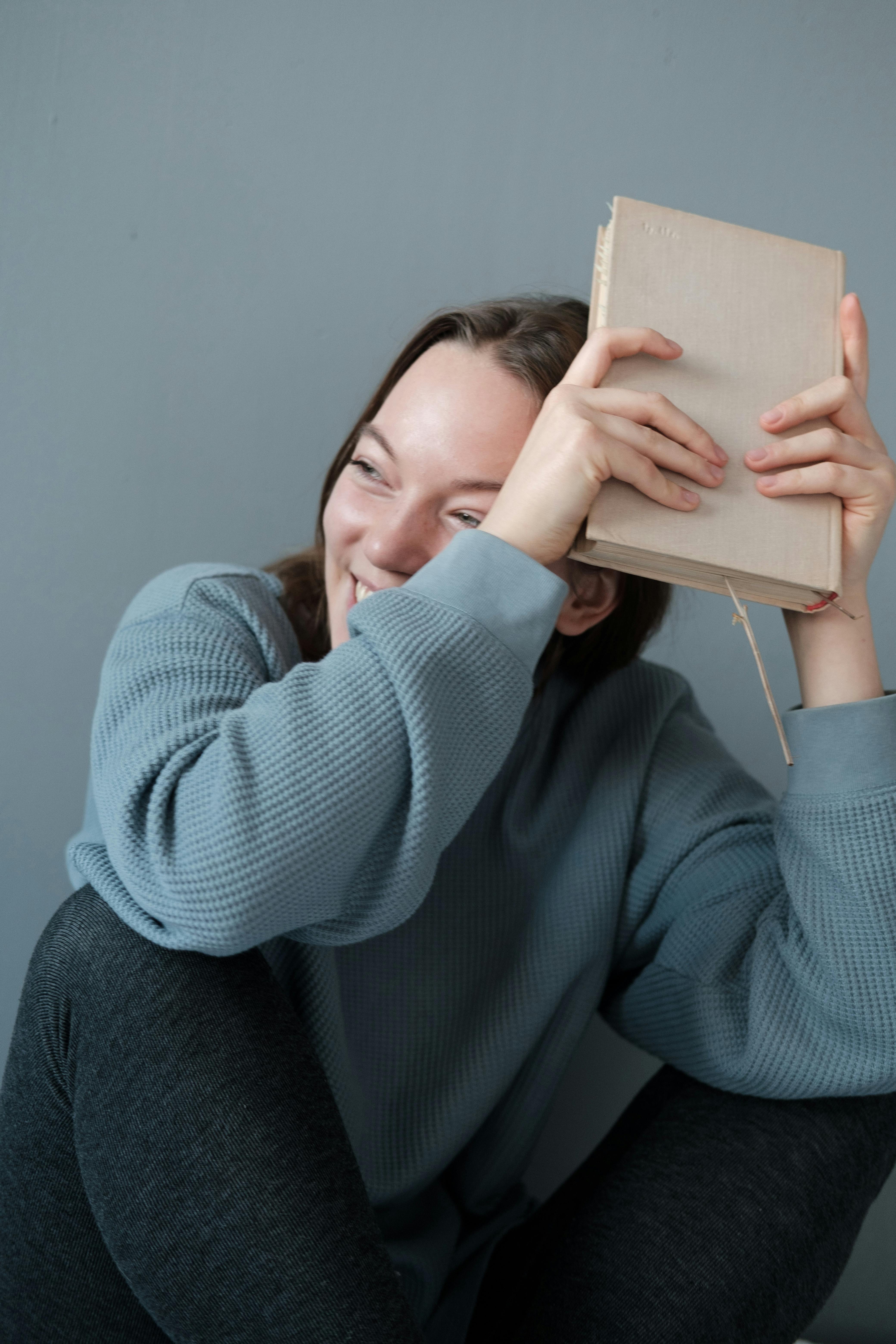 smiling woman in gray warm clothes sitting with book