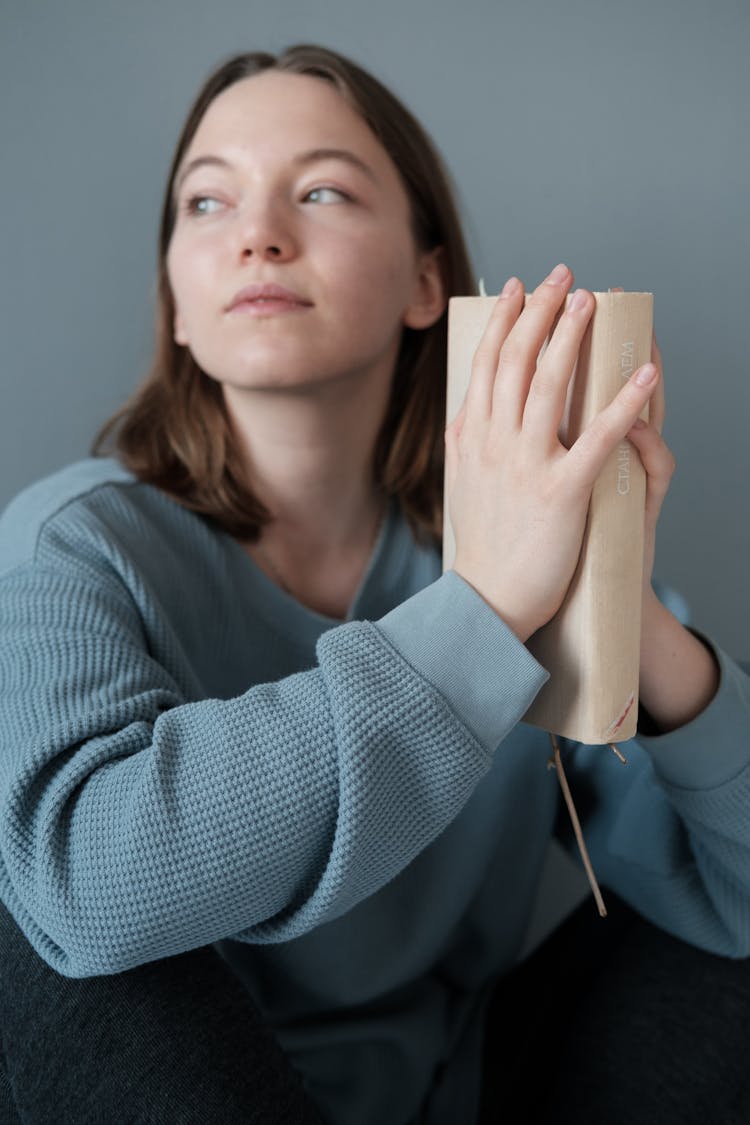 Young Woman In Knitted Jumper Sitting With Book