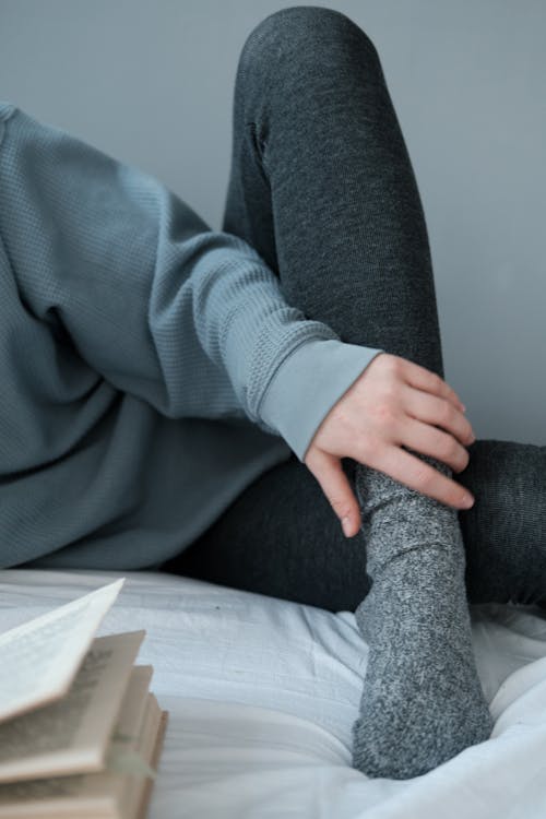 Person in Gray Long Sleeve Shirt and Black Pants Sitting on Black Chair